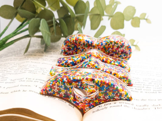 A quirky, rainbow sprinkle-covered thumb-shaped book page holder for fun reading sessions.