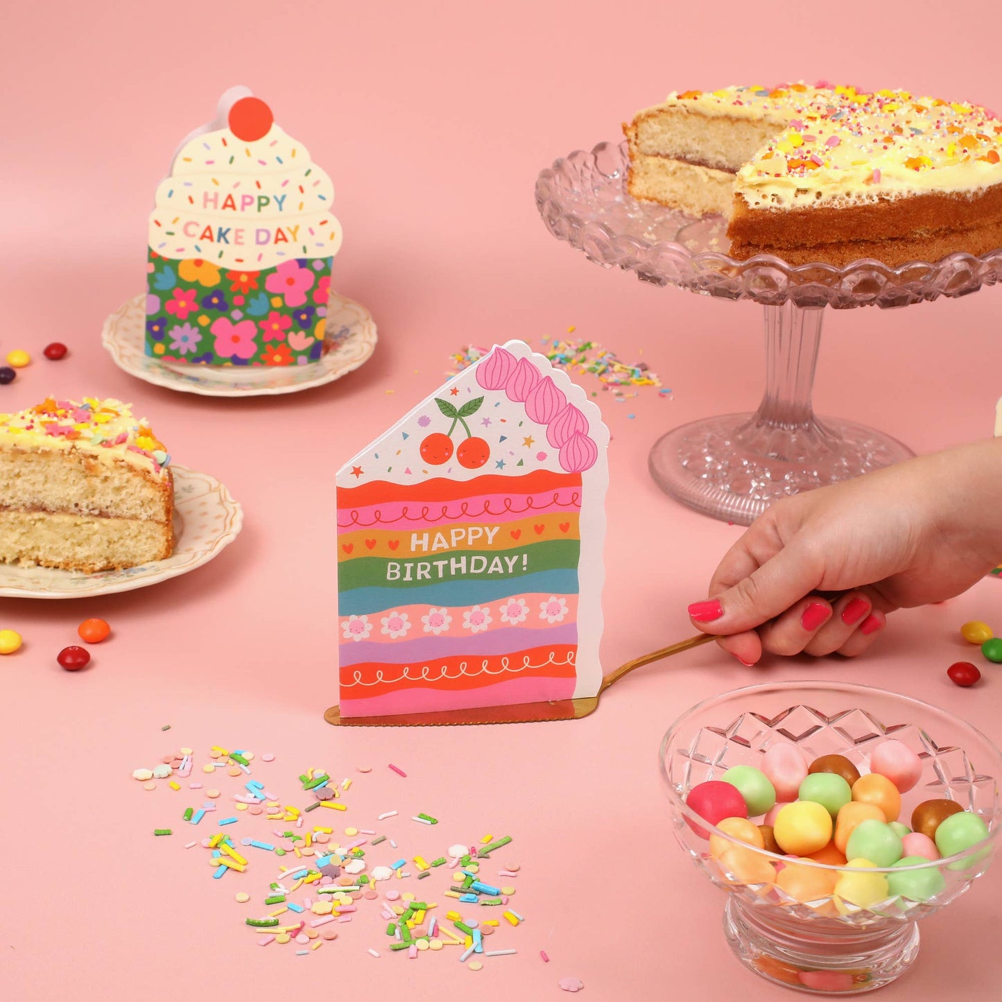 A colorful, die-cut birthday card shaped like a cake with a rainbow design and "Happy Birthday!" message.