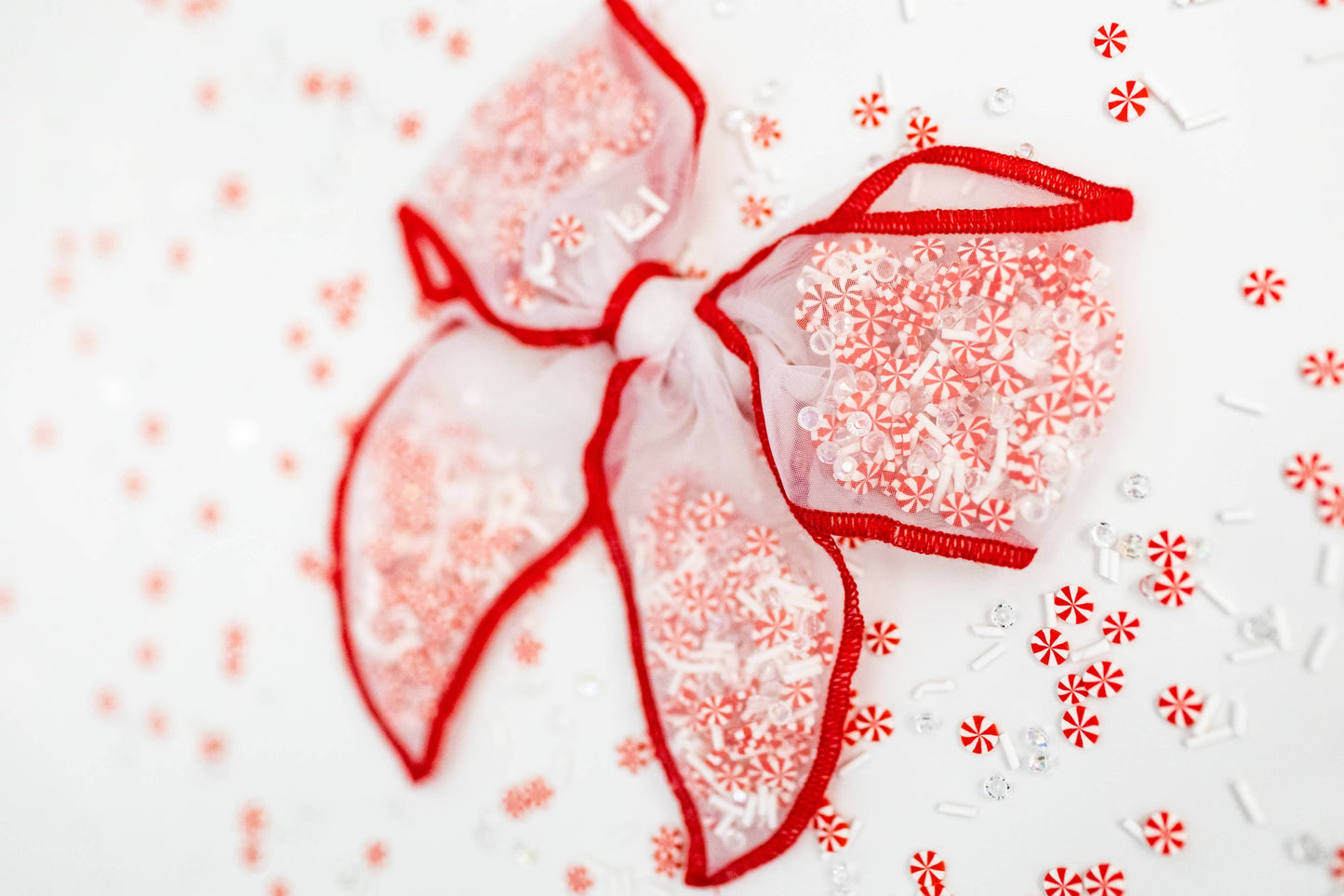 A festive red and white mesh bow filled with peppermint confetti, perfect for holiday cheer.