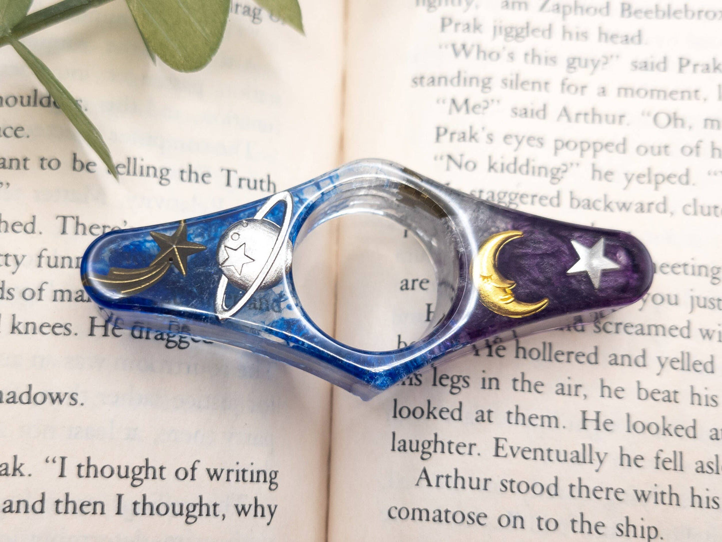 Purple and blue resin book page holder with galaxy design, featuring stars, moons, and planets.