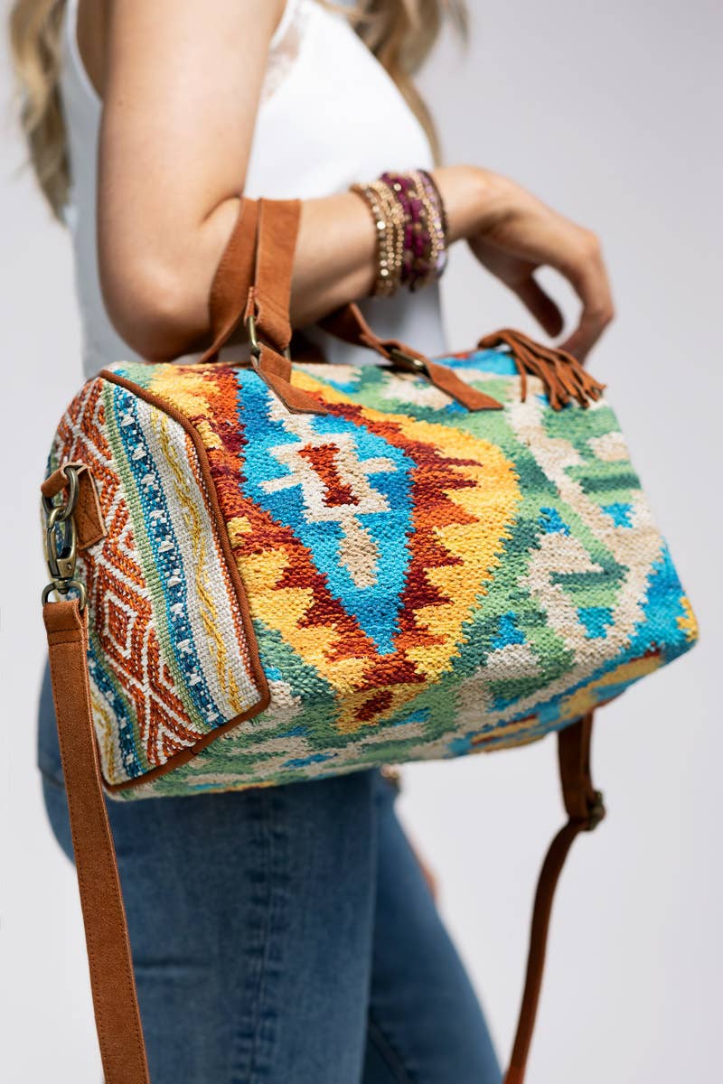 Colorful woven Boston-style duffel bag with geometric ethnic patterns and suede handles and strap.