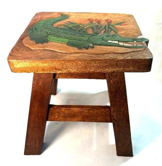 Hand-carved wooden stool featuring a green alligator design on the seat, perfect for unique adult gifts.