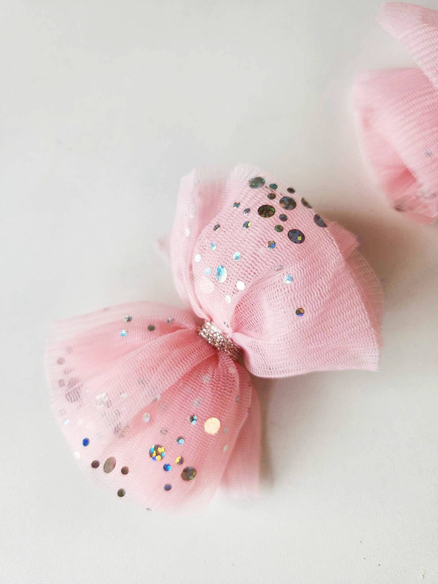 Pink tulle hair bow adorned with colorful sequins, perfect for girls.
