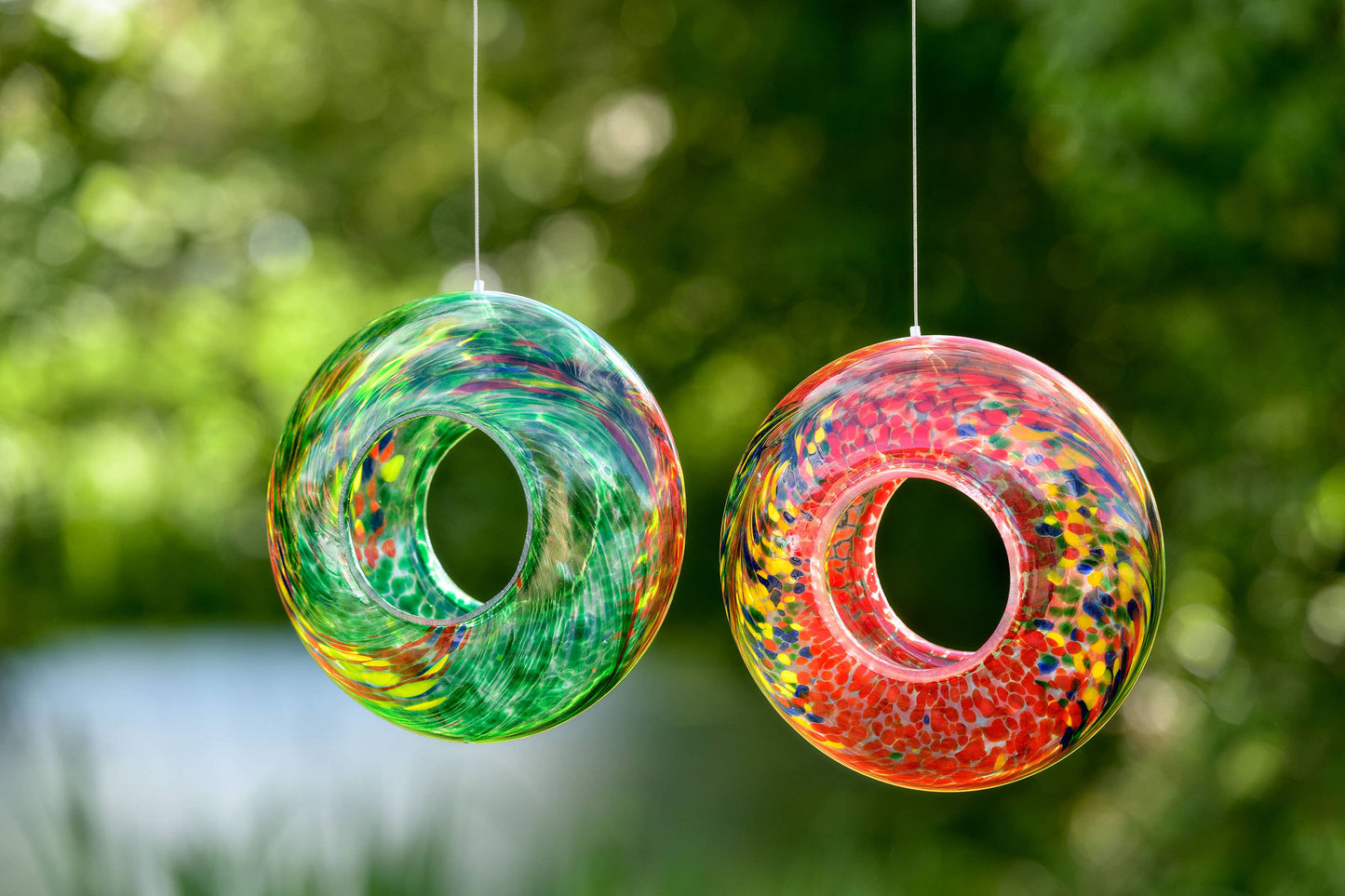 Hand-blown glass bird feeder in vibrant red with colorful speckles, perfect for outdoor hanging.