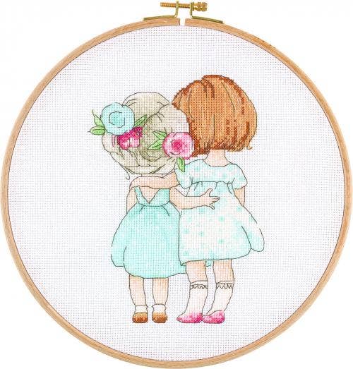 Cross stitch hoop kit showing two girls in pastel dresses hugging