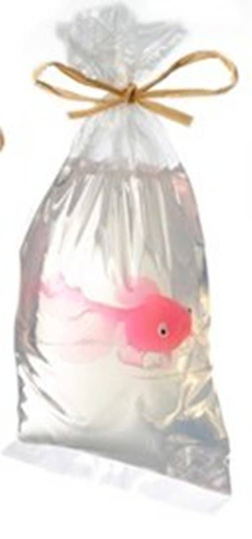 A pink fish-shaped soap nestled in a clear bag with a gold ribbon tie.