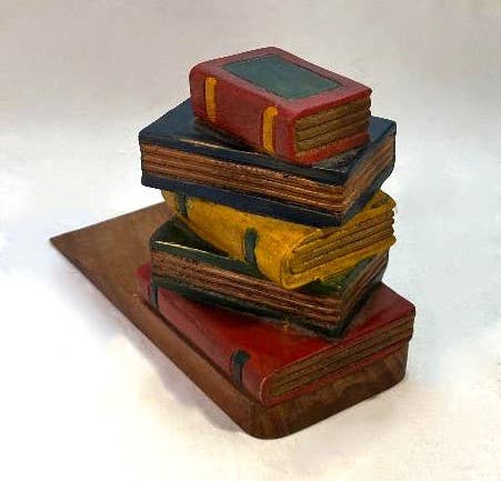 Hand-carved wooden doorstop shaped like a stack of vintage books in red, yellow, and blue.