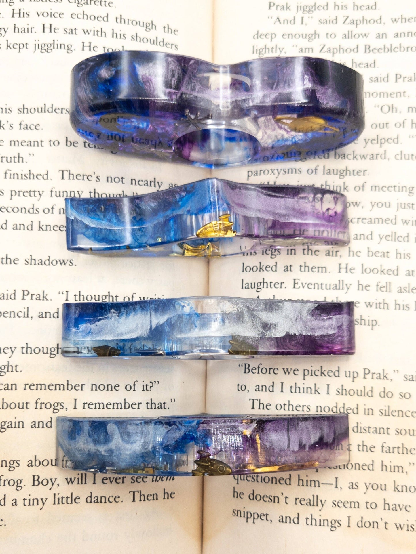 Purple and blue resin book page holders with galaxy-inspired swirls and metallic accents.