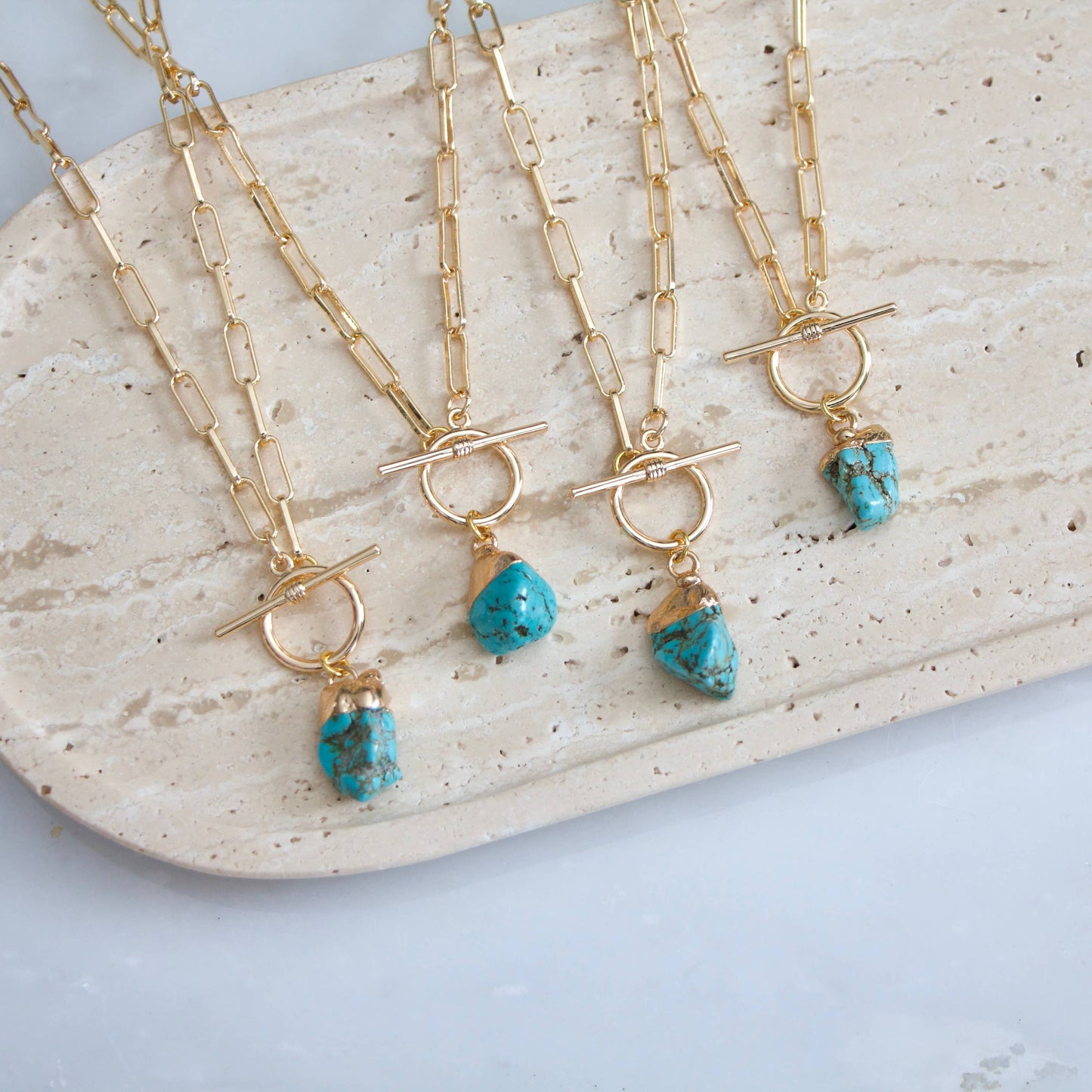 Gold paperclip chain necklace with a turquoise nugget pendant and a toggle clasp.