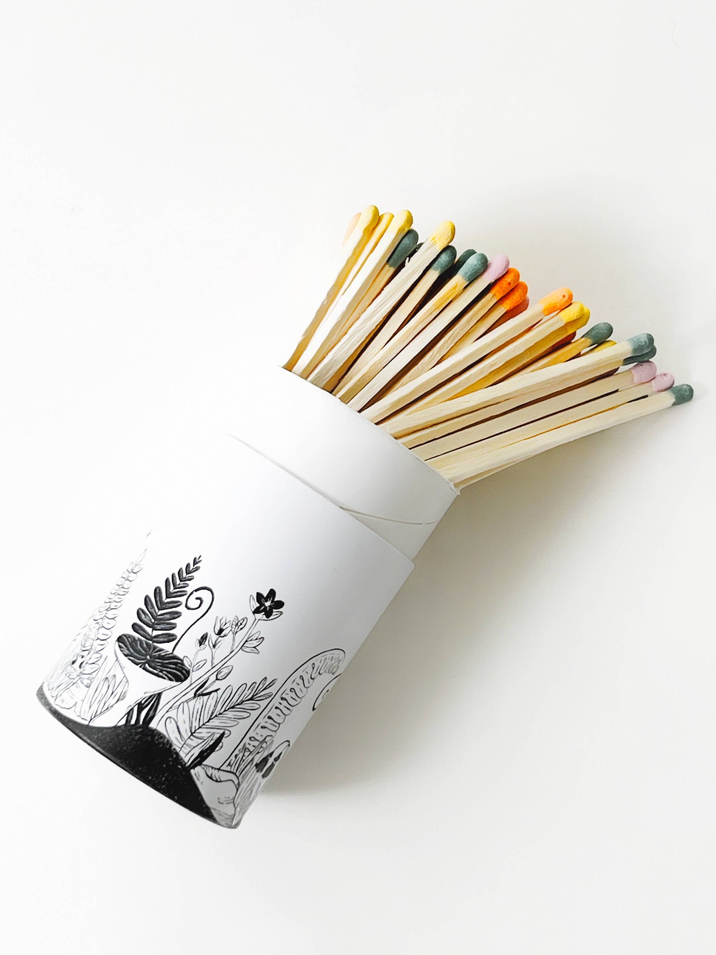 Pastel-colored long safety matches in a white botanical-patterned tube.