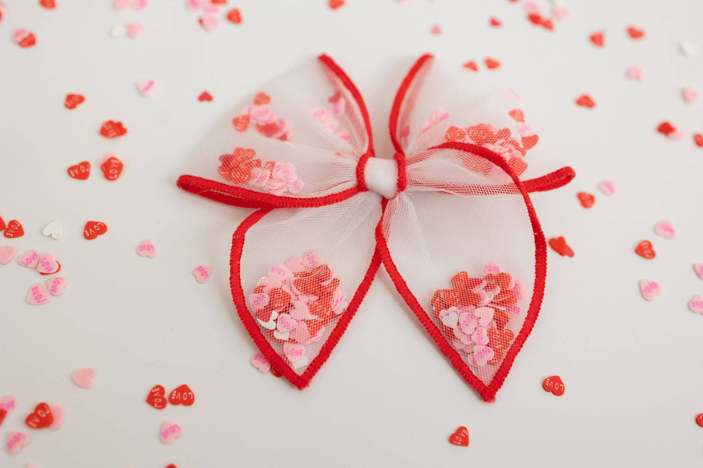 A small red and white mesh bow filled with heart-shaped confetti, perfect for Valentine's gifts.