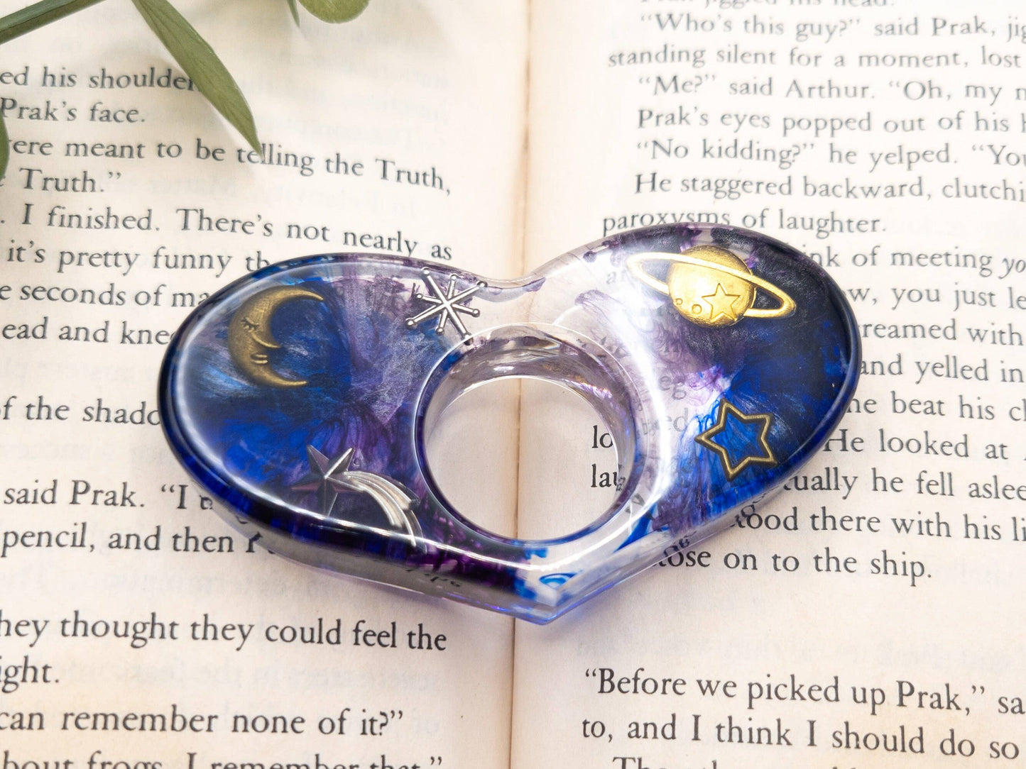 Purple and blue resin book page holder with galaxy design, featuring stars, moon, and planet details.