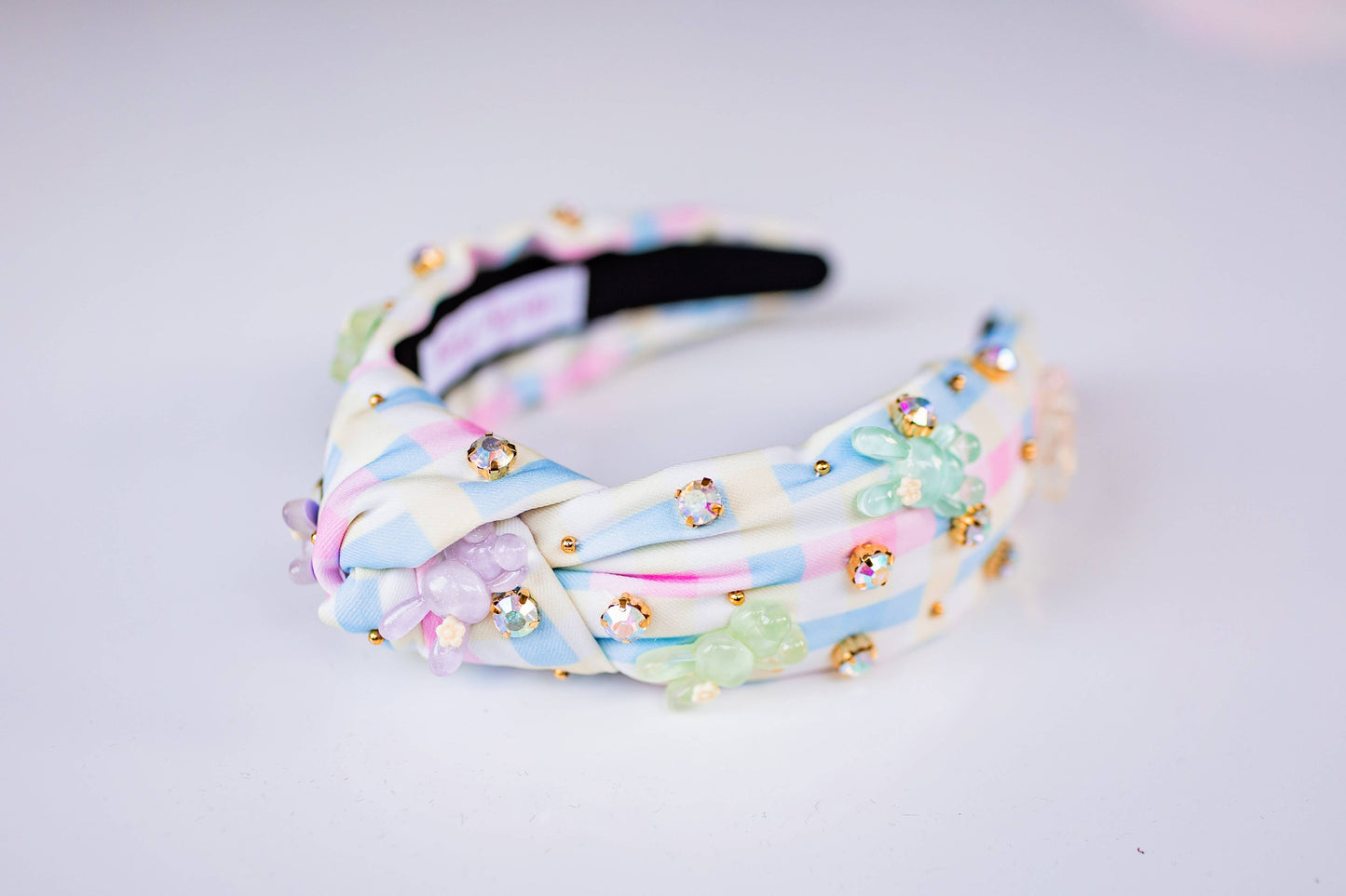 Pastel plaid knotted headband with 3D bunny charms and jewel accents in soft spring colors.