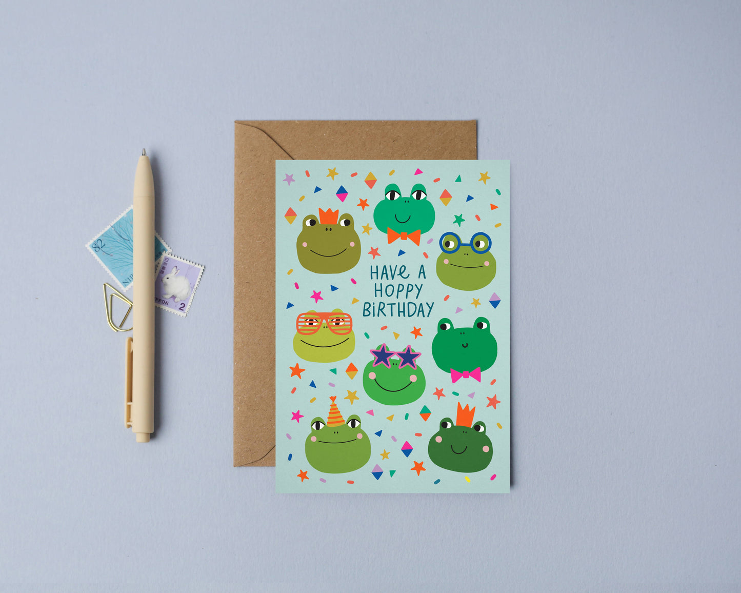 Illustrated birthday card with playful frog characters wearing party hats and glasses