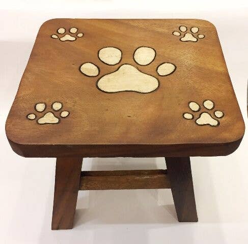 Square wooden stool with carved puppy paw prints on the seat