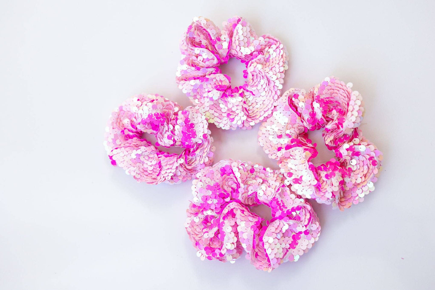 Pink and white iridescent sequin scrunchies that shimmer in the light, creating a magical sparkling effect.