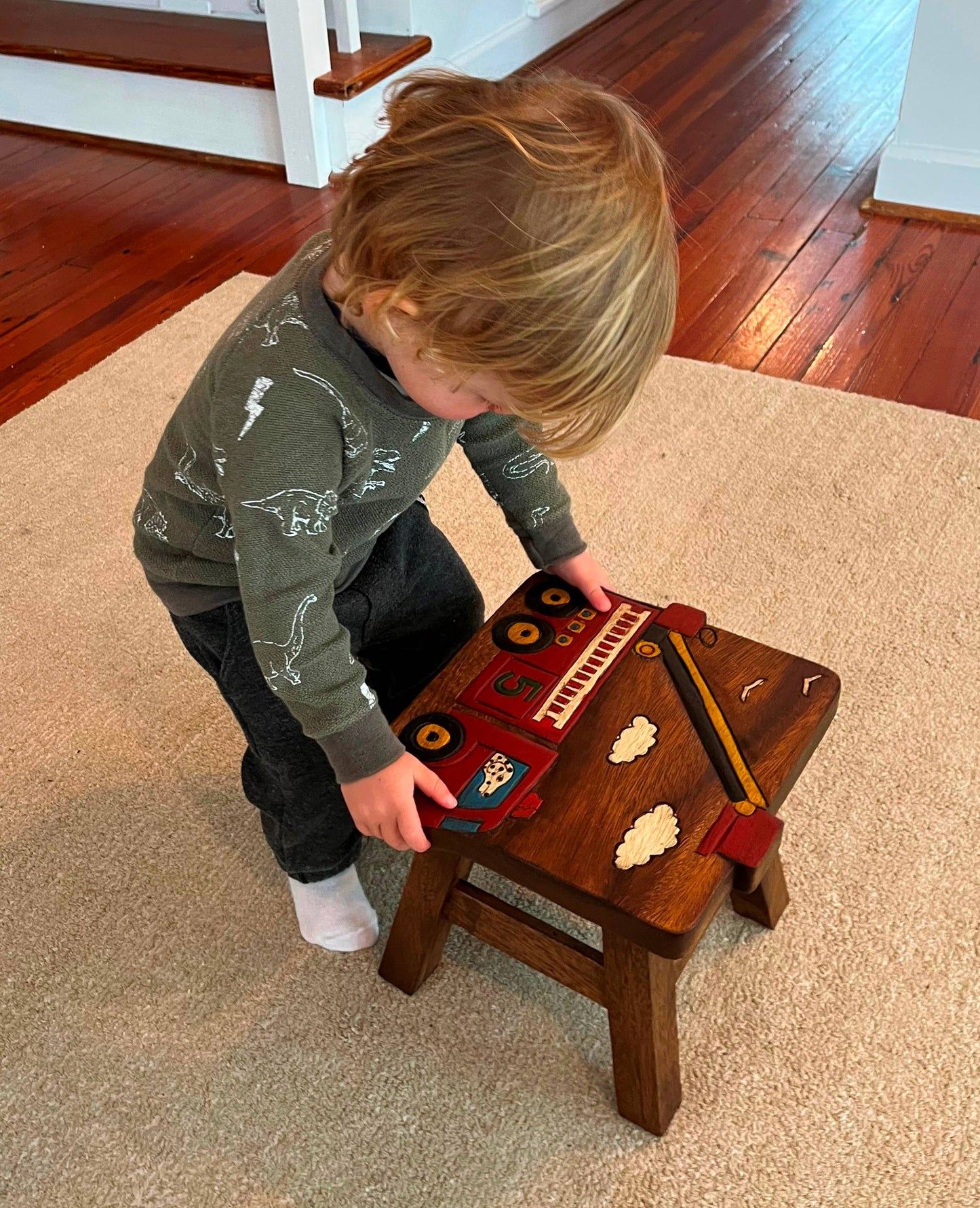 Wooden stool with colorful fire truck carving, perfect for kids' rooms.