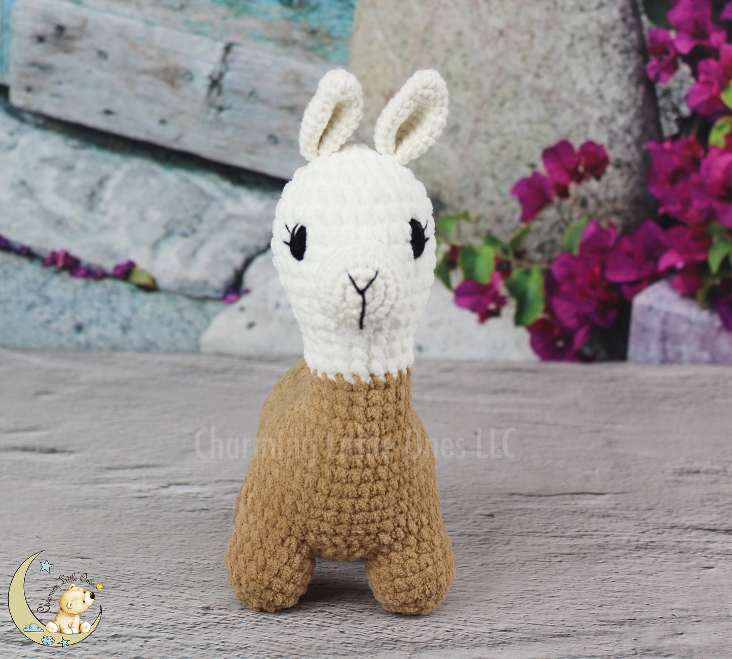 A handmade crochet llama toy with a white face and brown body, standing on a wooden surface.