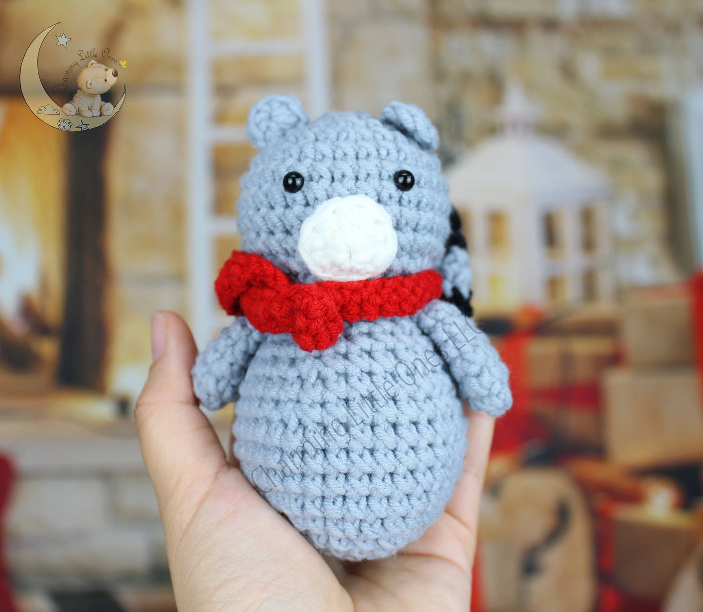 Crocheted raccoon Christmas ornament in gray with a white snout and red bow tie.