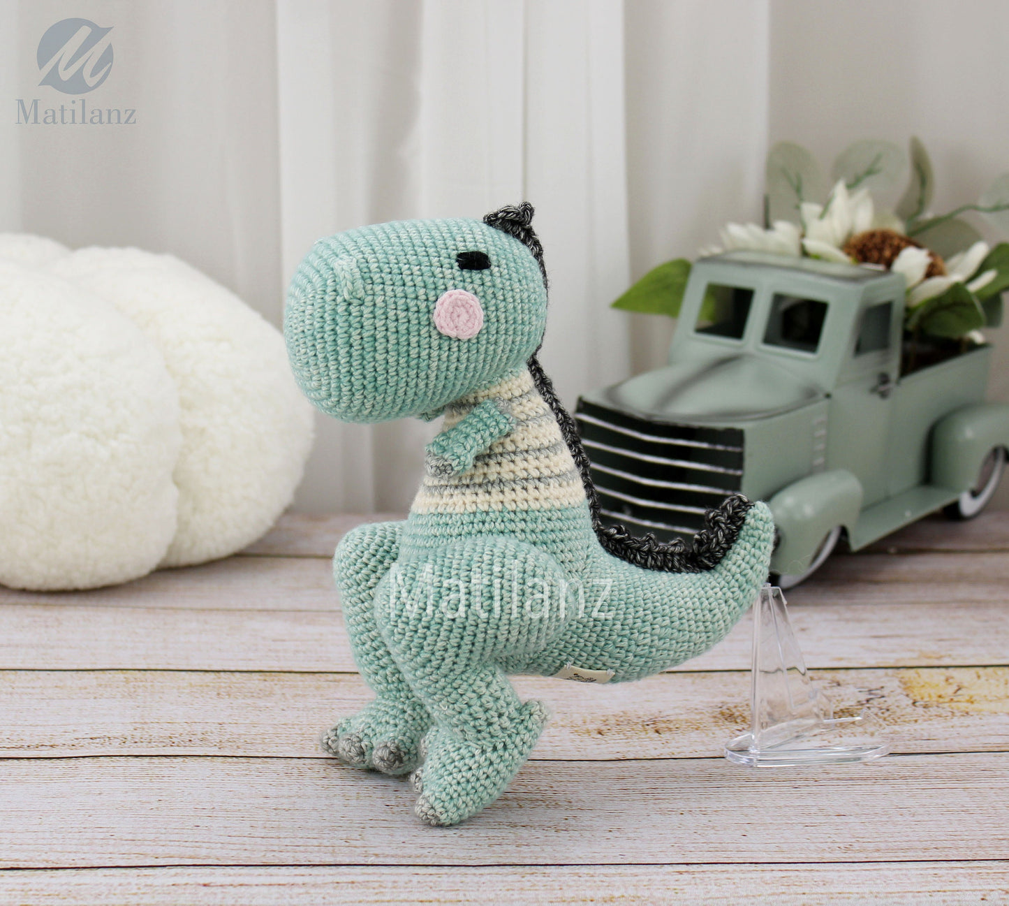 Handmade crochet T-Rex dinosaur in mint green with striped details, perfect for play or decoration.