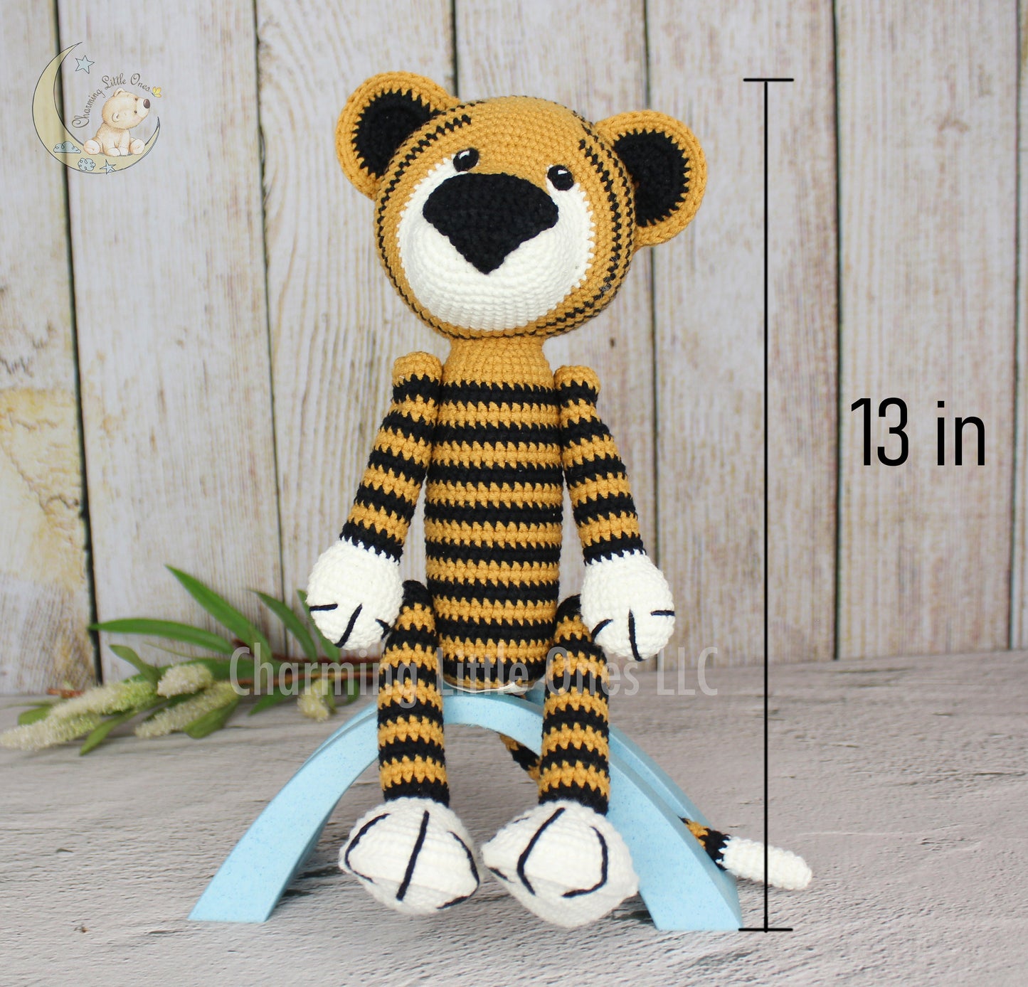 A handmade crochet tiger toy with yellow and black stripes, sitting on a stand.