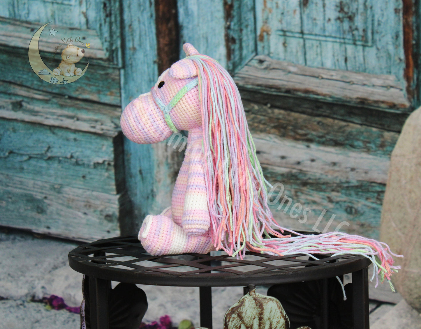 A charming pink crochet horse with a colorful mane and tail, perfect for cuddling.