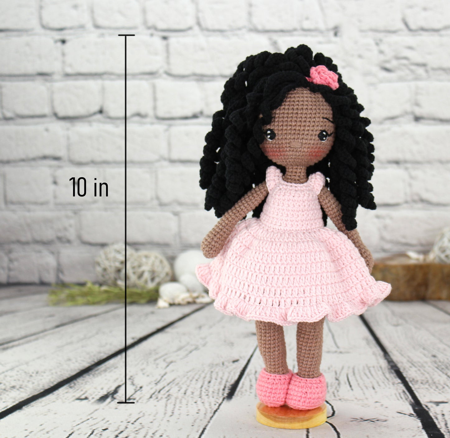 A handmade crochet African American doll with black hair, pink dress, and shoes, standing 10 inches tall.
