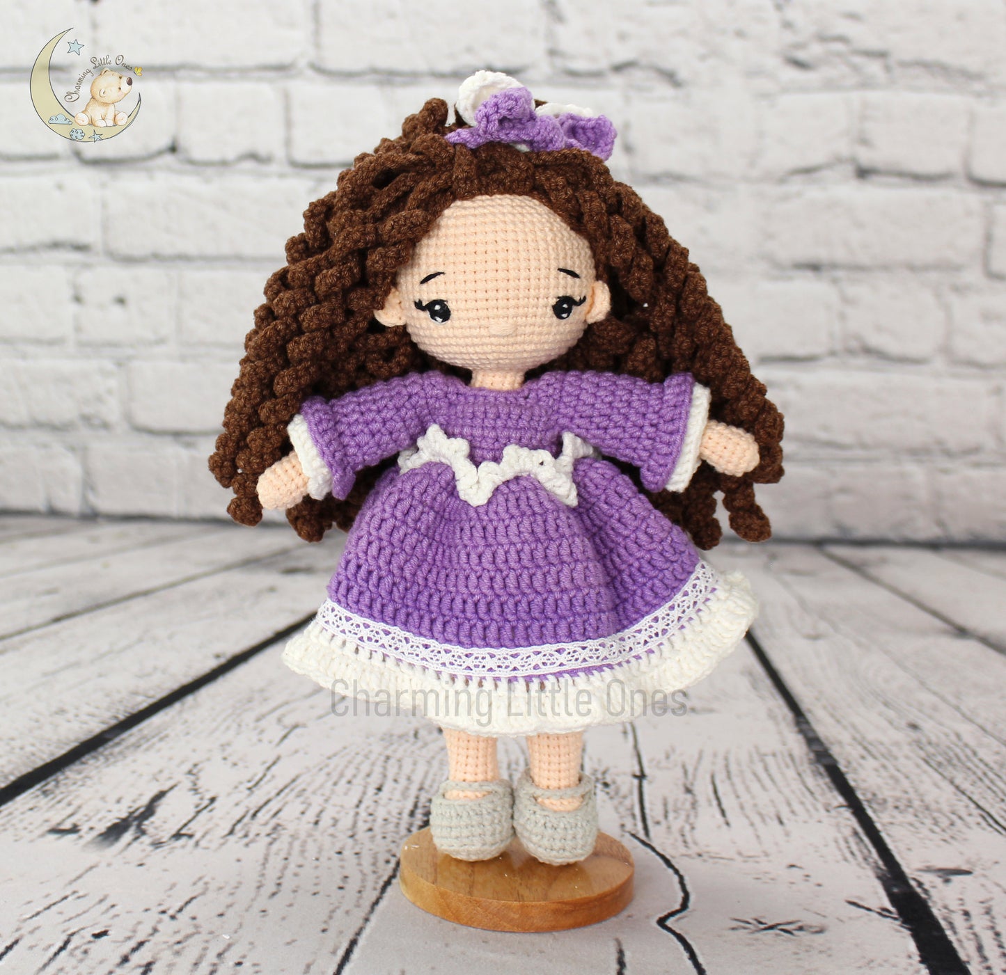 Handmade crochet doll with brown curly hair, purple dress, and white lace trim, standing 10 inches tall.