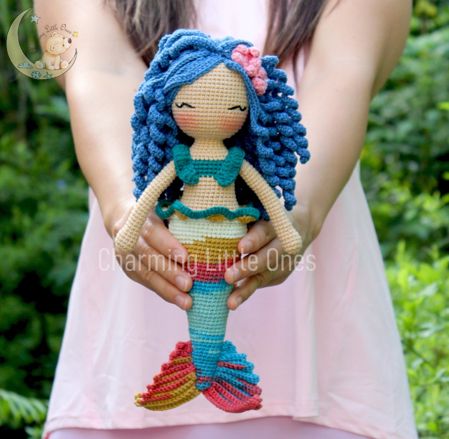 A handmade crochet mermaid doll with blue hair, green top, and rainbow tail.