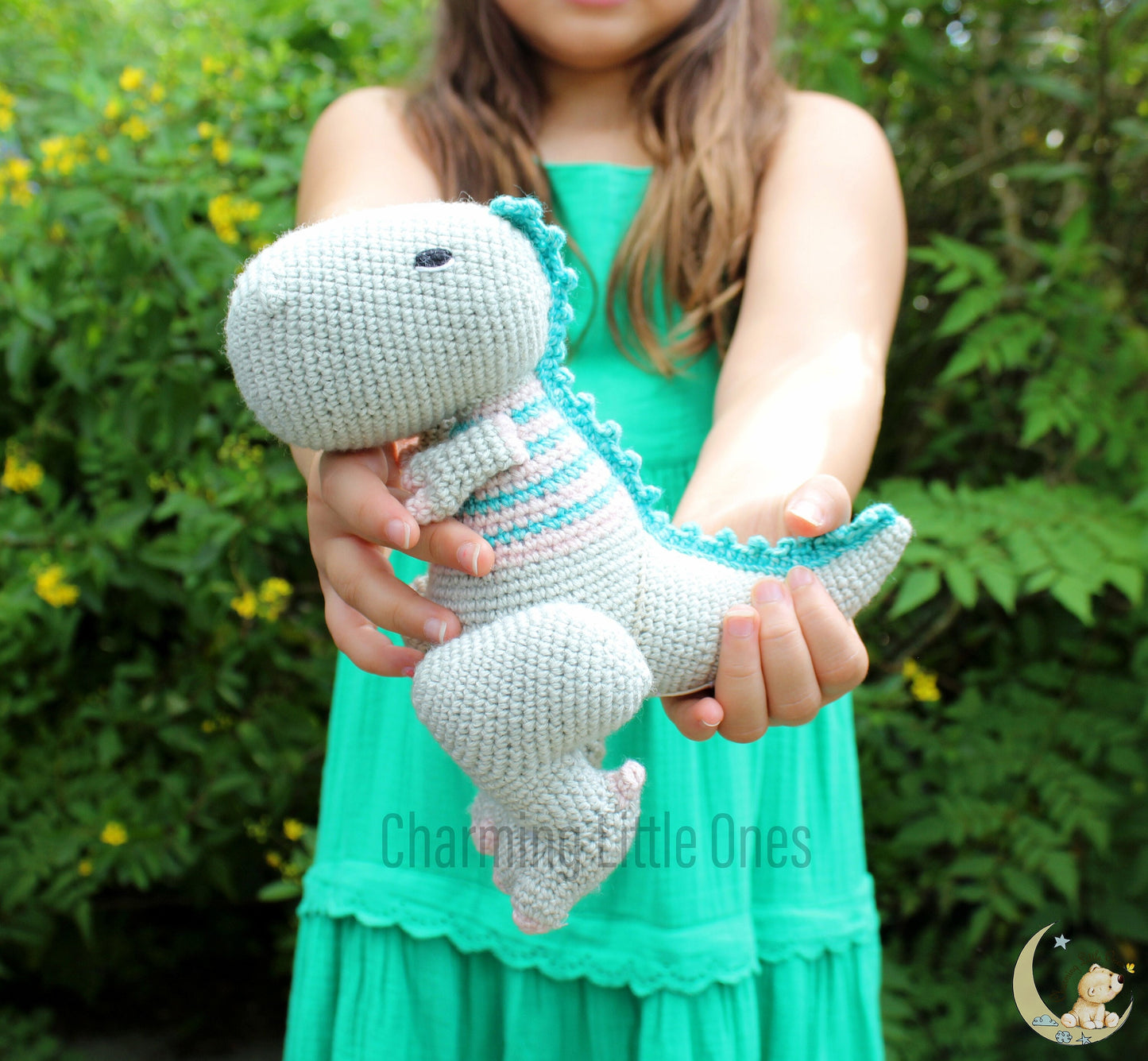 Handmade crochet T-Rex dinosaur, 8 inches tall, with soft gray body and colorful striped details.