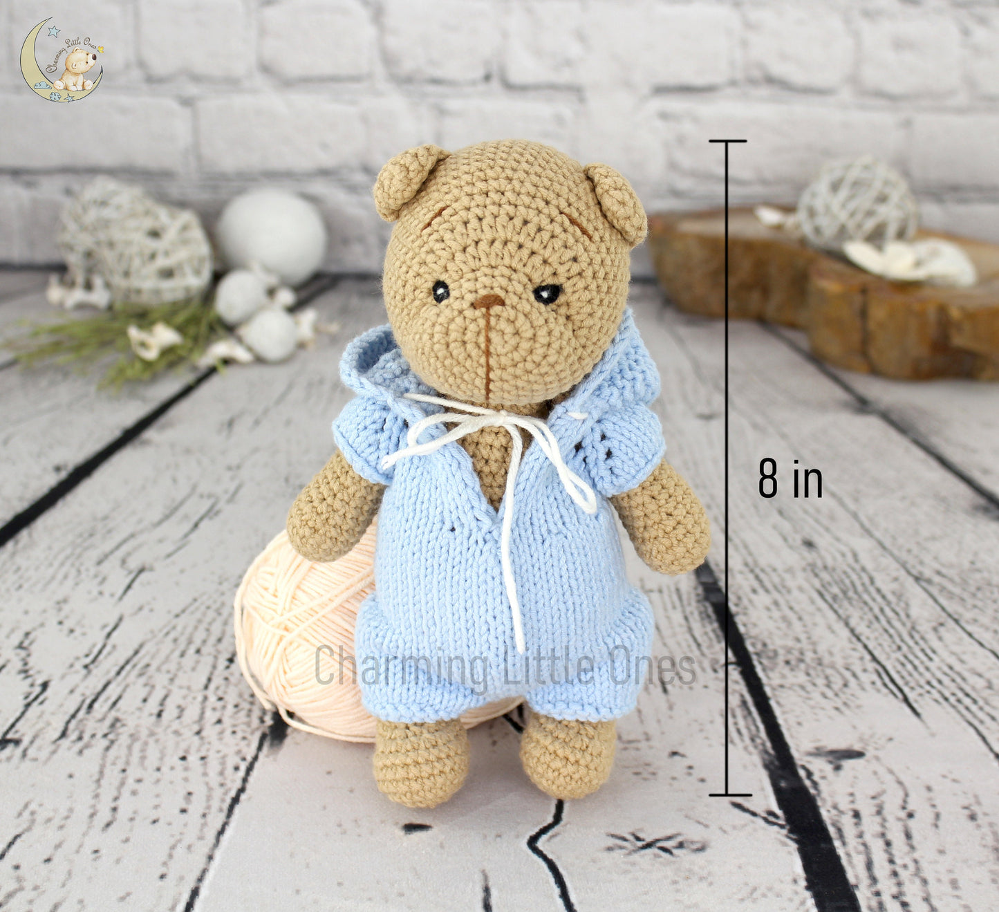 A handmade 8-inch teddy bear in a light blue knitted robe, crafted with care.