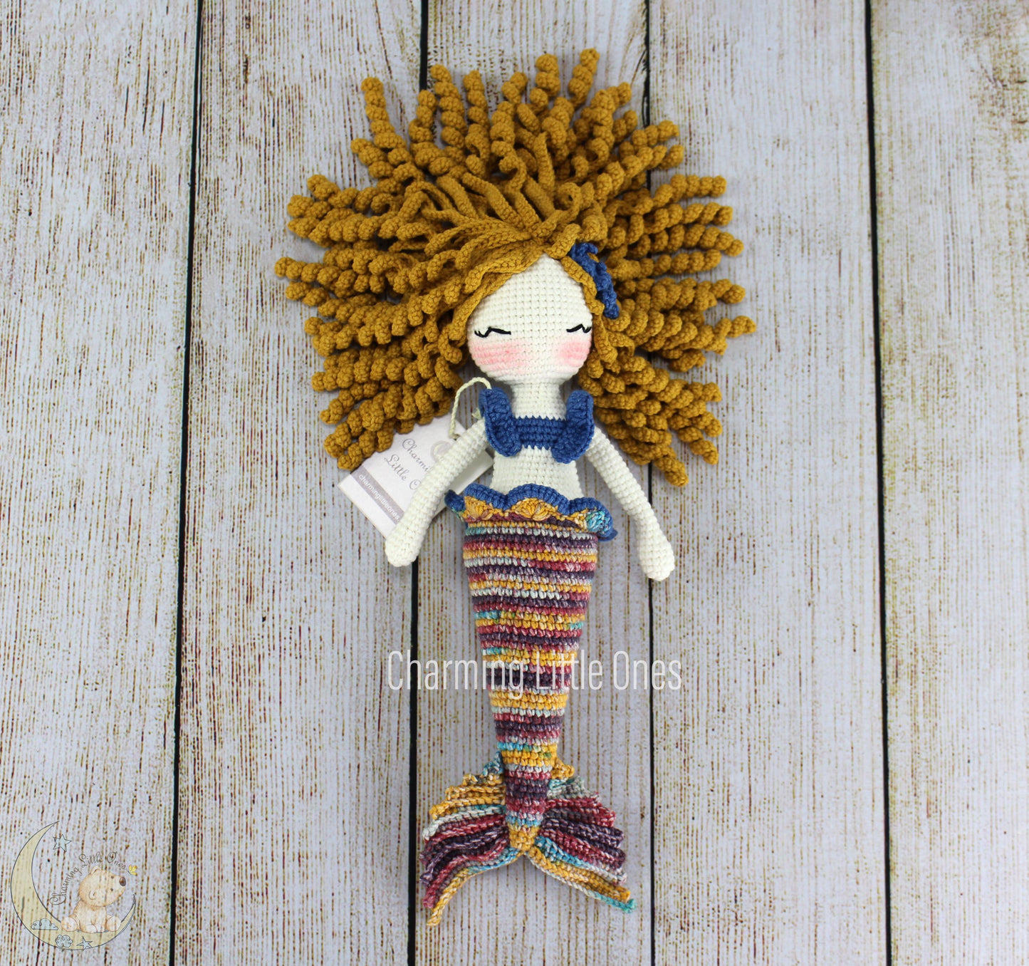 A handmade crochet mermaid doll with golden hair, blue top, and multicolored striped tail, 12 inches tall.