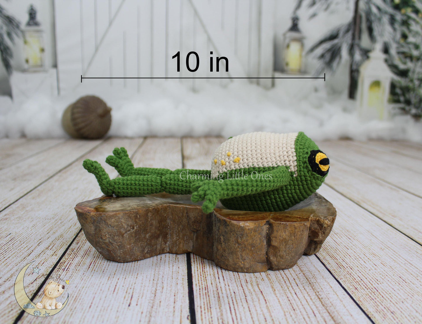 A handmade crochet frog with green body and cream head, featuring large yellow eyes, resting on a wooden slice.