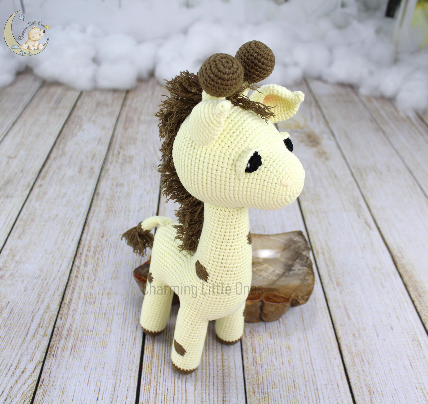 A handmade crochet giraffe with brown spots and a fluffy mane, standing on a wooden base.