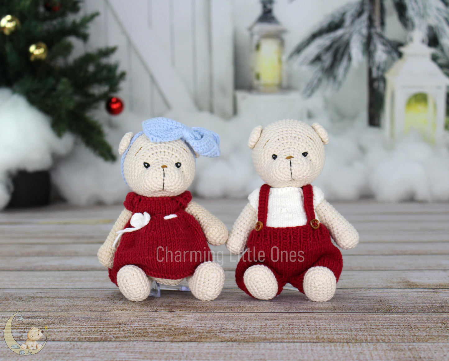 Two handmade crochet Christmas bears, one in a red dress with a blue bow, the other in red overalls, sitting on a wooden surface.