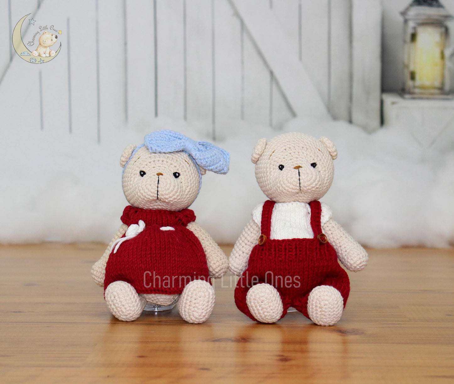 Two handmade crochet Christmas bears, one in a red dress with a blue hat and the other in red overalls, sitting on a wooden floor.