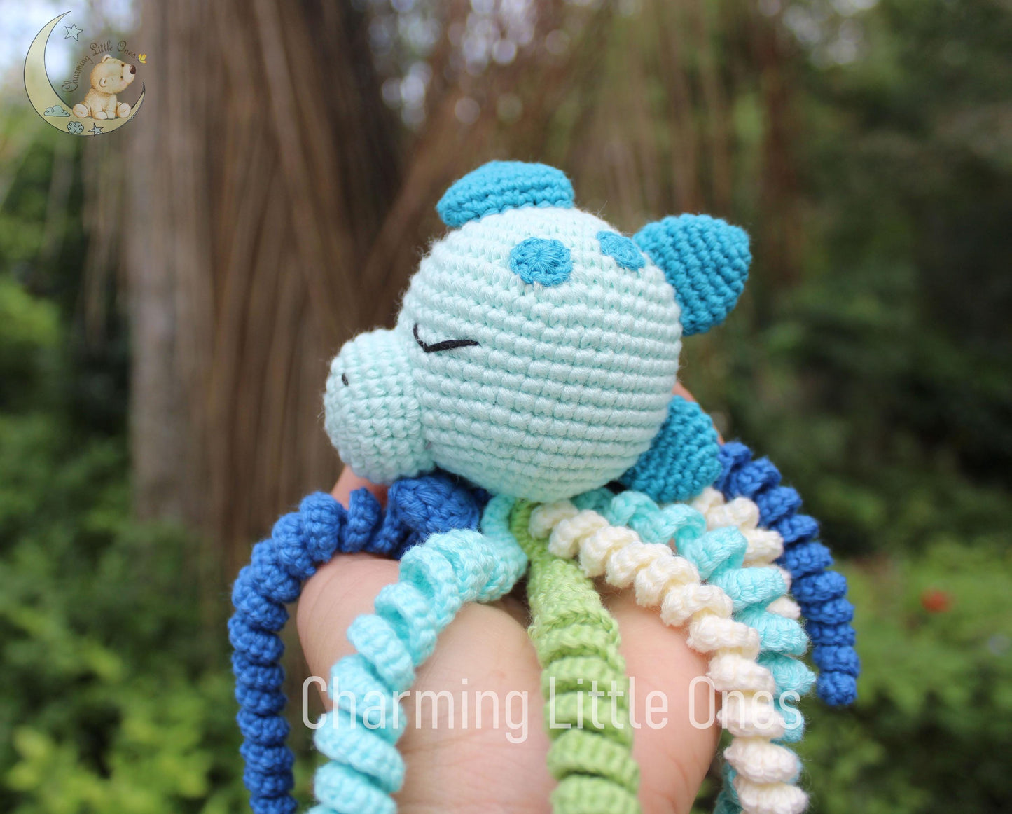 A handmade crochet octopus with light blue body, blue and white tentacles, and a smiling face.