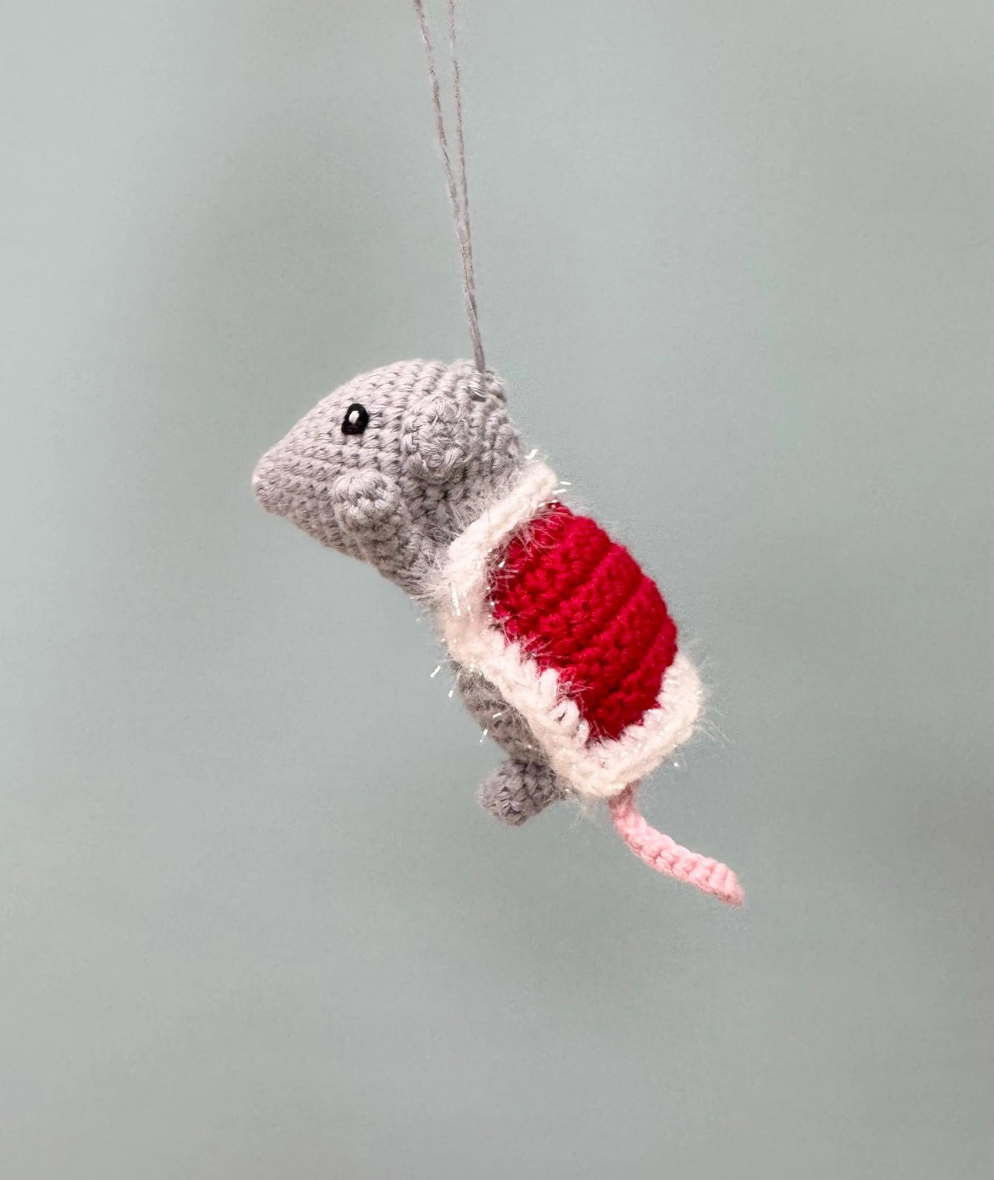 Crochet mouse ornament in gray with a red and white present, perfect for Christmas decorating.