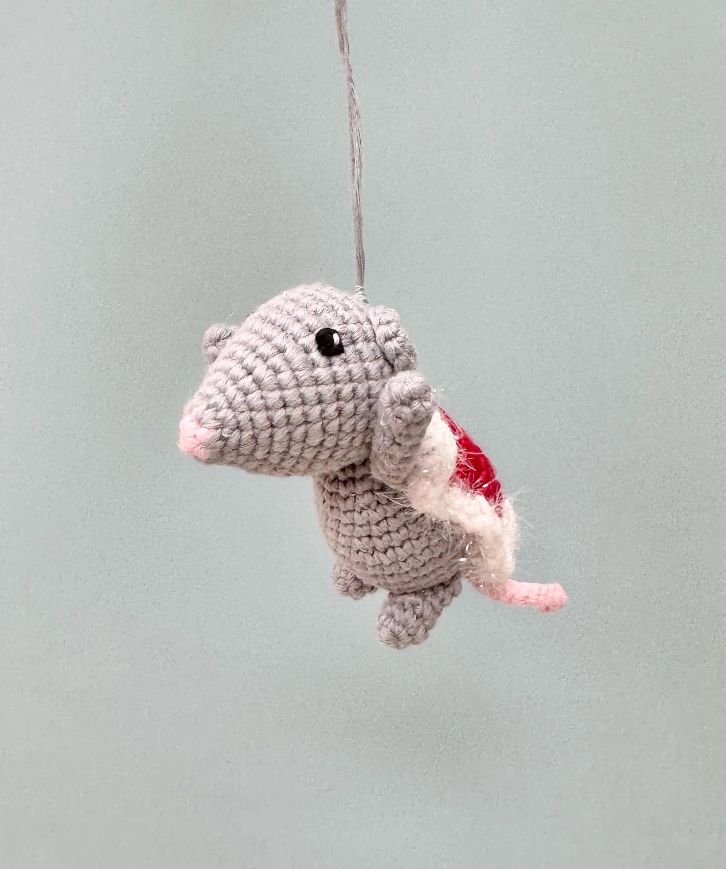 Crochet mouse ornament holding a red Christmas present, perfect for festive tree decoration.