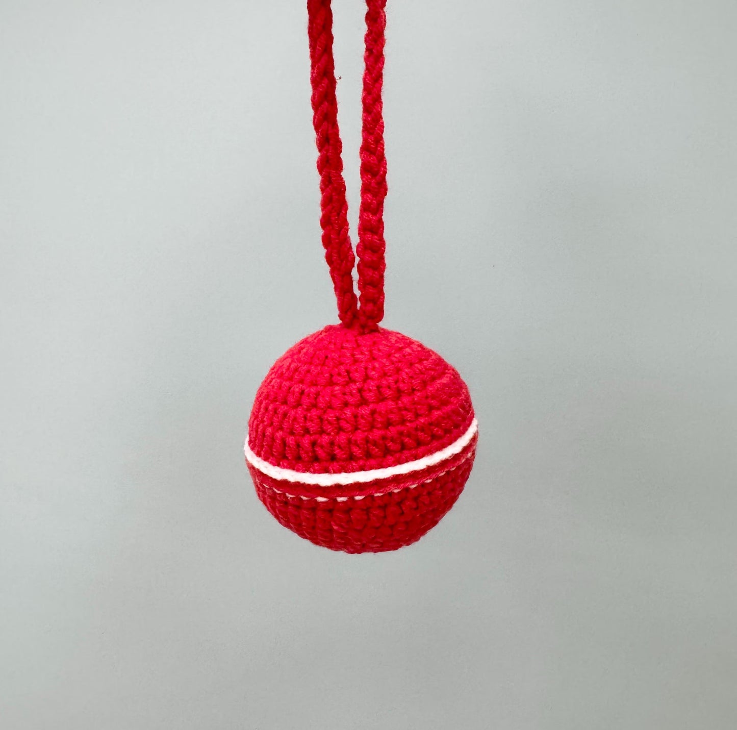 Handmade red crochet Christmas ball with white stripe, perfect for tree decorations.
