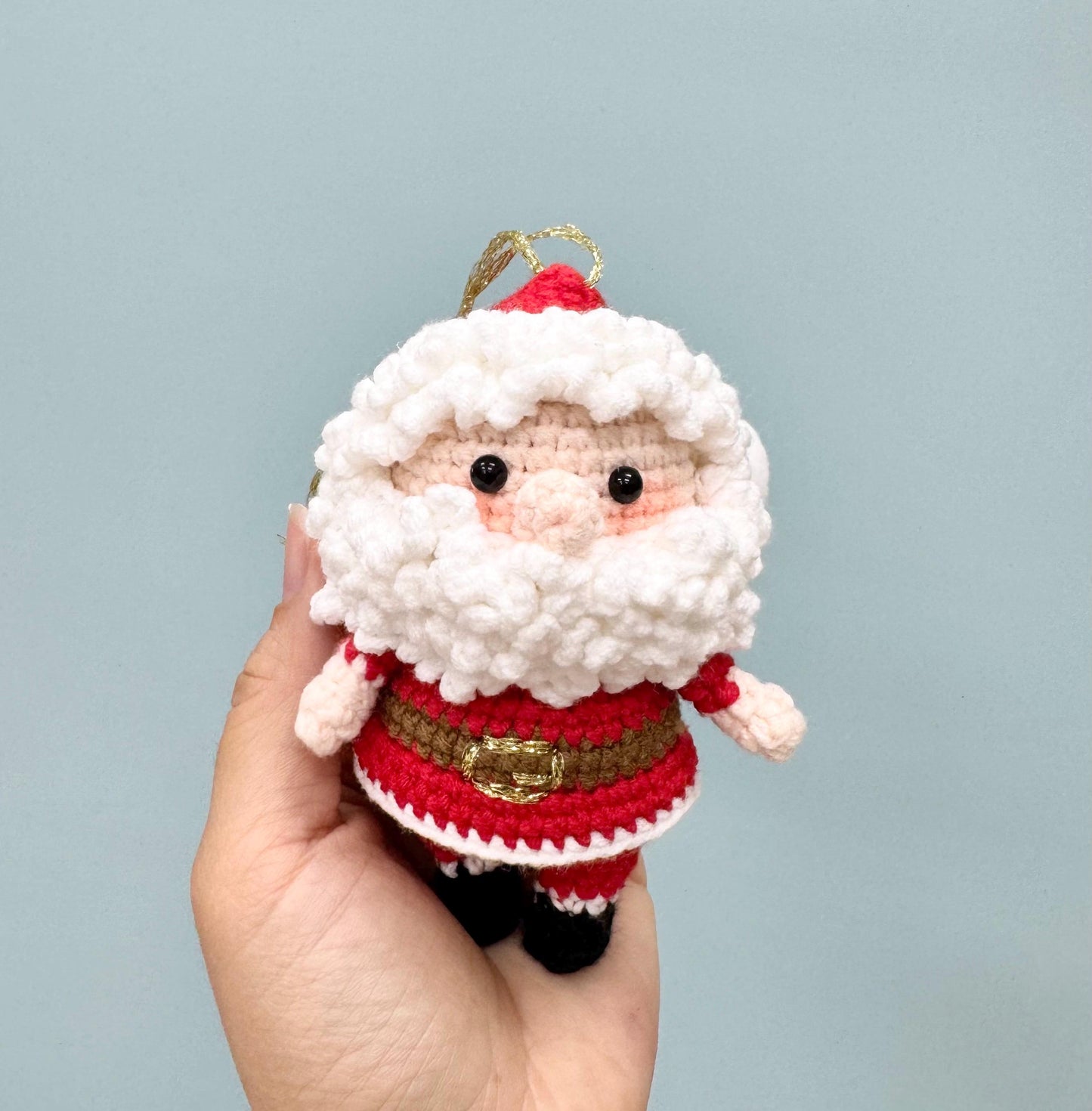 Crochet Santa Claus ornament with a red suit, white beard, and gold buckle, perfect for holiday decorating.