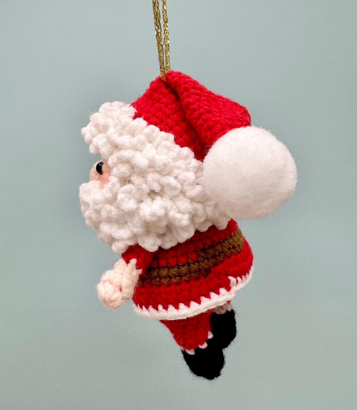 Crochet Santa Claus ornament with a red suit, white beard, and gold hanging string.
