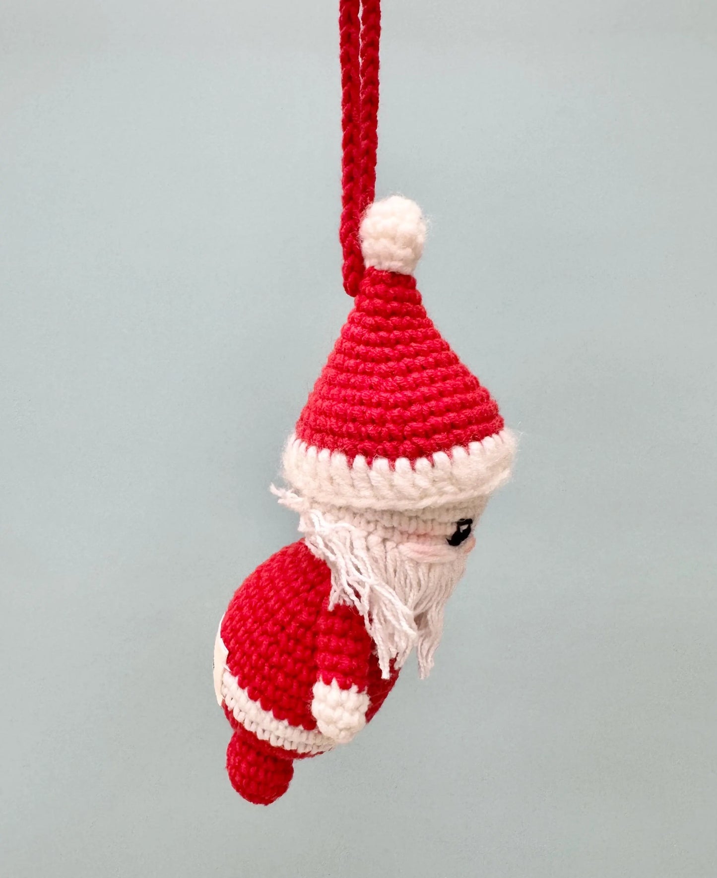 Handmade crochet Santa Claus ornament with red and white details, featuring a fluffy beard and festive hat.