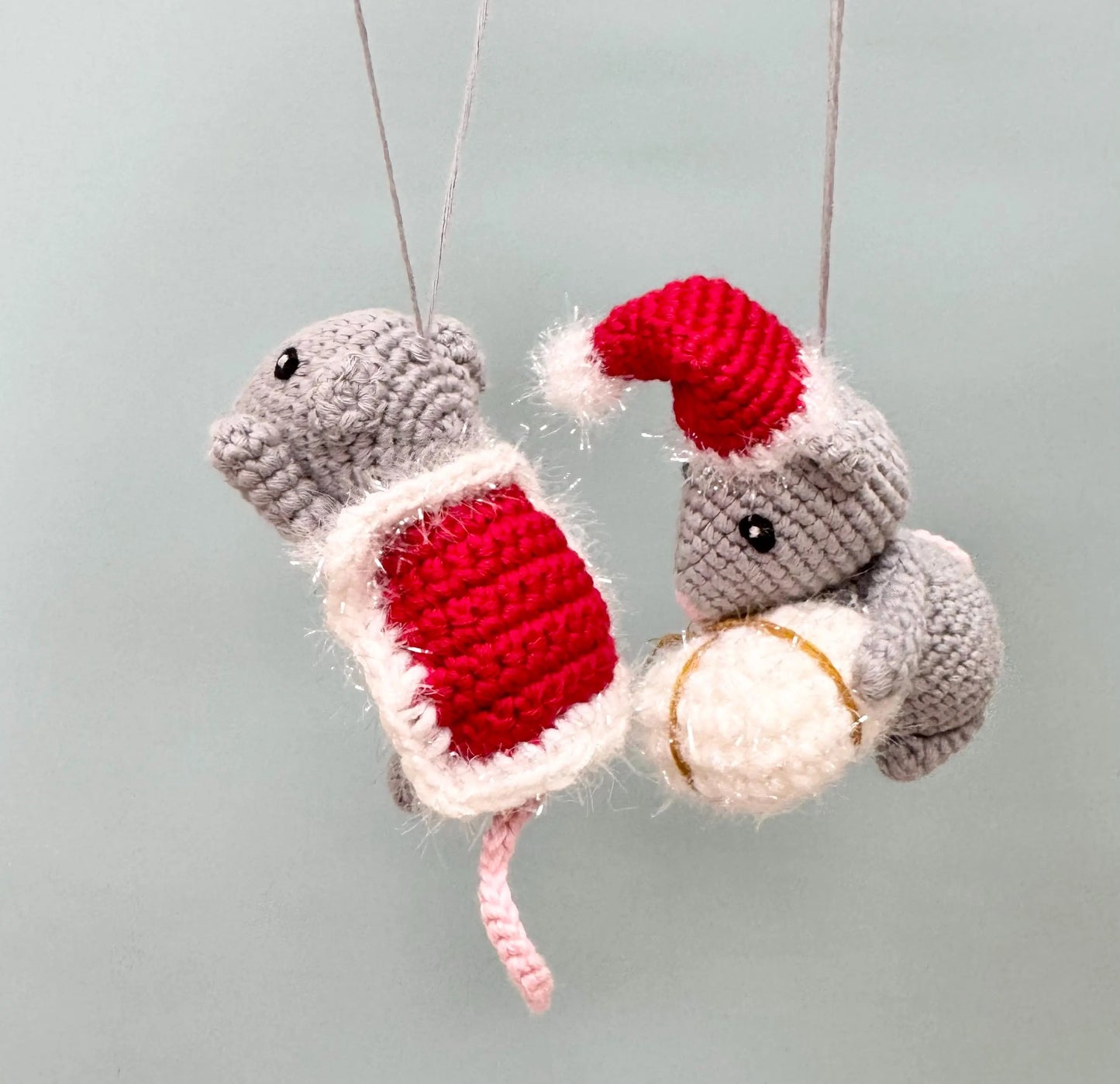 Crochet mouse ornament holding a red present, wearing a Santa hat, perfect for Christmas decorating.