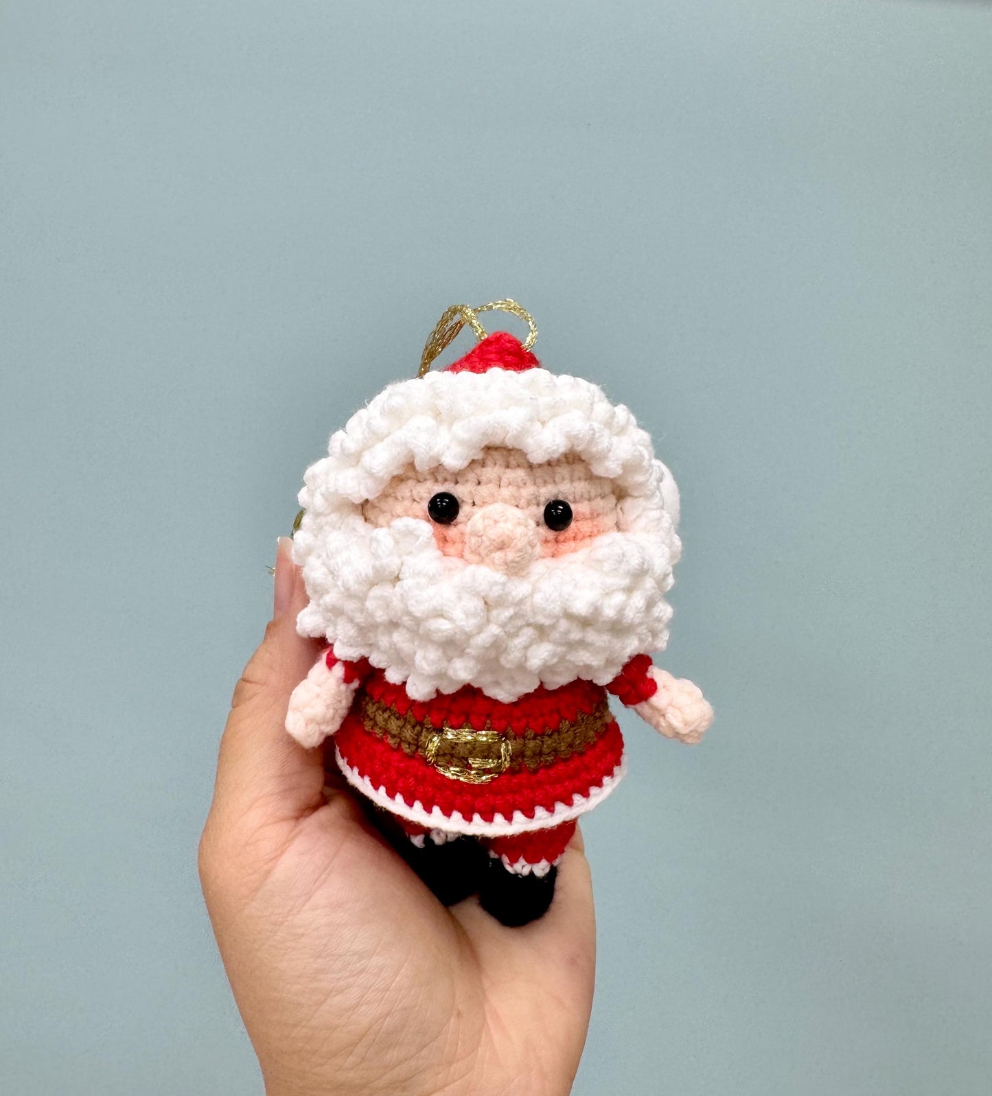 Crochet Santa Claus ornament with a red suit, white beard, and gold belt, perfect for holiday decorating.