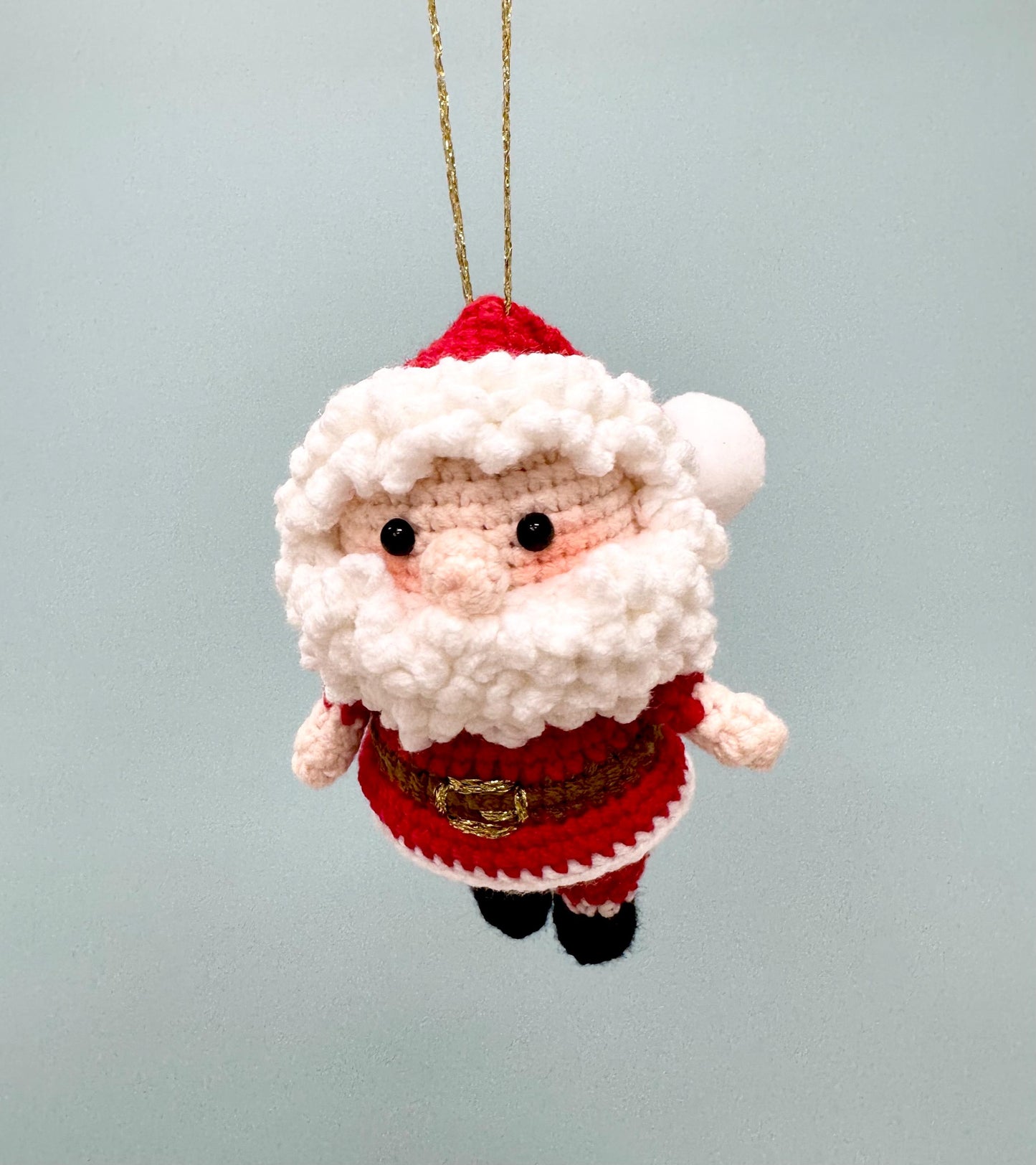 Crochet Santa Claus ornament with red suit, white beard, and gold belt, perfect for holiday decorating.