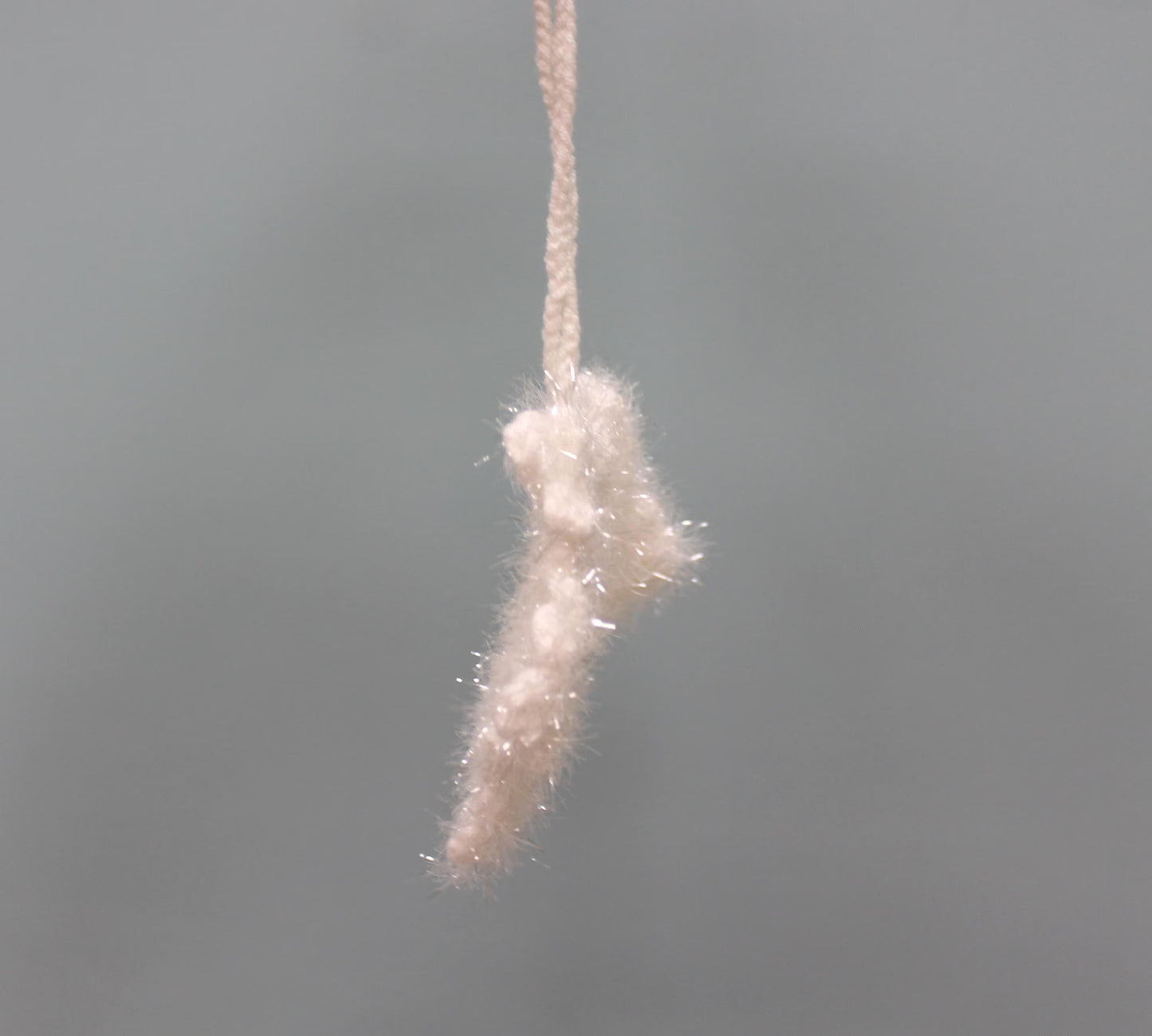 Handmade crochet snowflake Christmas ornament in white, featuring a fluffy texture and a hanging loop.