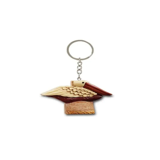 Wooden keychain with a hand-carved pelican standing on a wooden piling, crafted from light and dark wood tones.