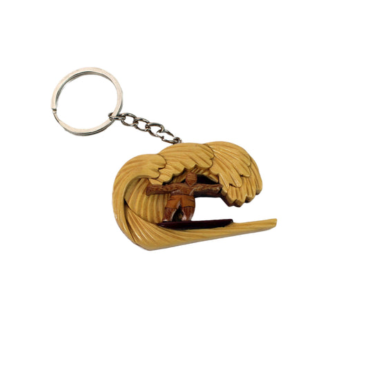 Hand-carved wood keychain of a surfer riding inside a curling wave, with layered light and dark wood grain.