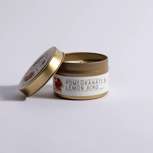 Gold tin candle labeled Pomegranate & Lemon Rind with open lid